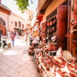 Traditional copperware shop in the heart of Fez Medina, Morocco, showcasing handcrafted pots, teapots, and tagines on a bustling street.